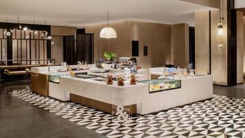 A modern hotel lobby with a central reception desk, a seating area, and a patterned floor.