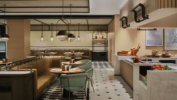 A modern restaurant with a central dining area, a bar, and a kitchen.