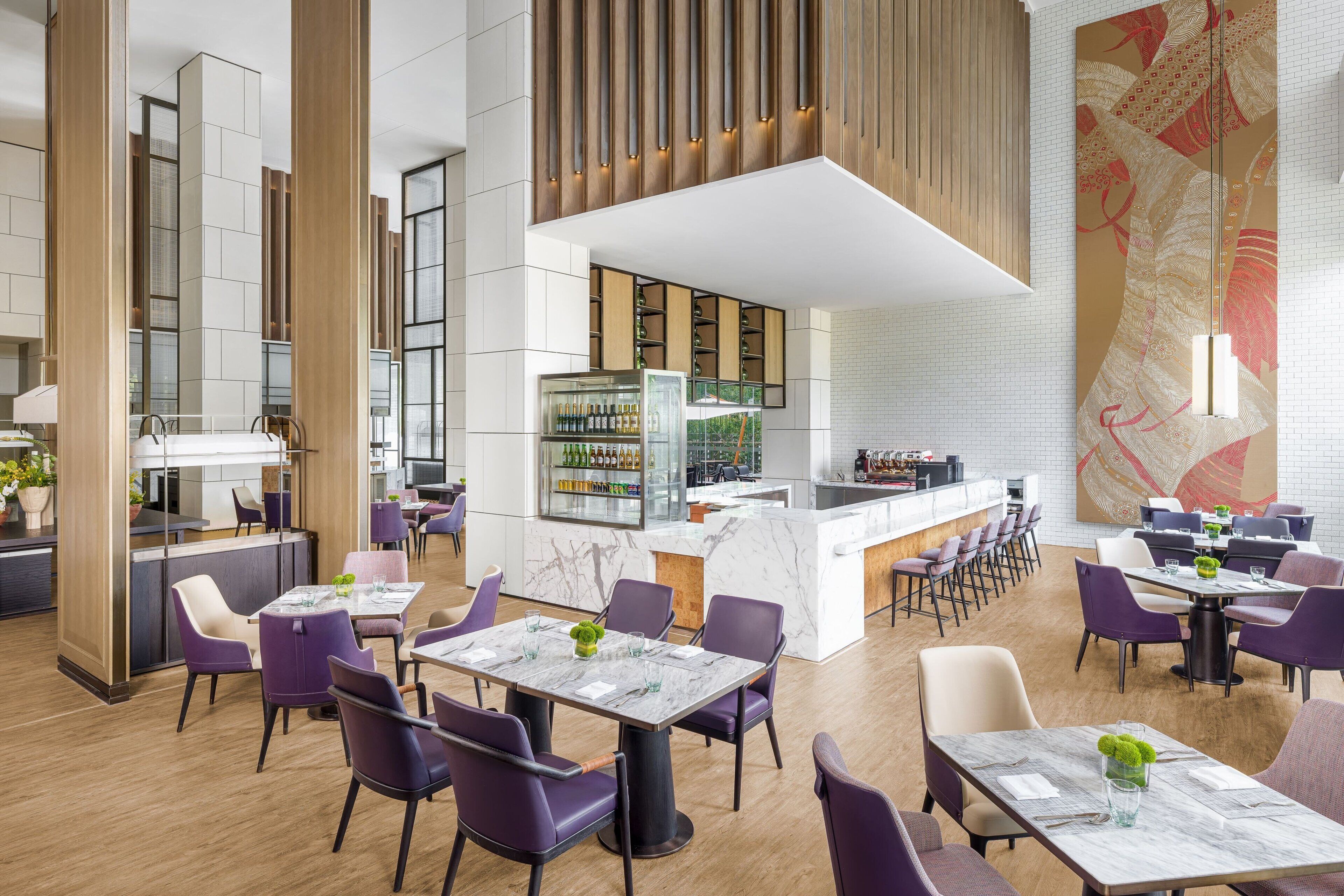 Un restaurante moderno con mesas de mármol, sillas moradas y una zona de bar central.