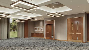Una espaciosa sala de conferencias con alfombra estampada, luces empotradas en el techo, paneles de madera y puertas grandes.