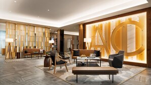 A modern hotel lobby with a large wooden wall, a seating area with sofas and chairs, and a coffee table. - AC Hotel By Marriott Newtown Square (Newtown Square)