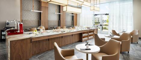 A modern kitchen with a central island, wooden cabinets, and a seating area with round tables and chairs.