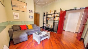 Ein Wohnzimmer mit grauem Sofa, einem Couchtisch und einem Bücherregal.
