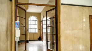 Ein Flur mit Fliesenboden, einem großen Bogenfenster und Glastüren mit Holzrahmen.