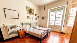 Ein Schlafzimmer mit zwei Betten, einem Heizkörper, einem Fenster und einer Tür.