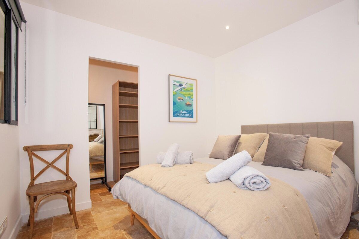 Une chambre à coucher avec un lit, une chaise, une armoire et une affiche accrochée au mur.