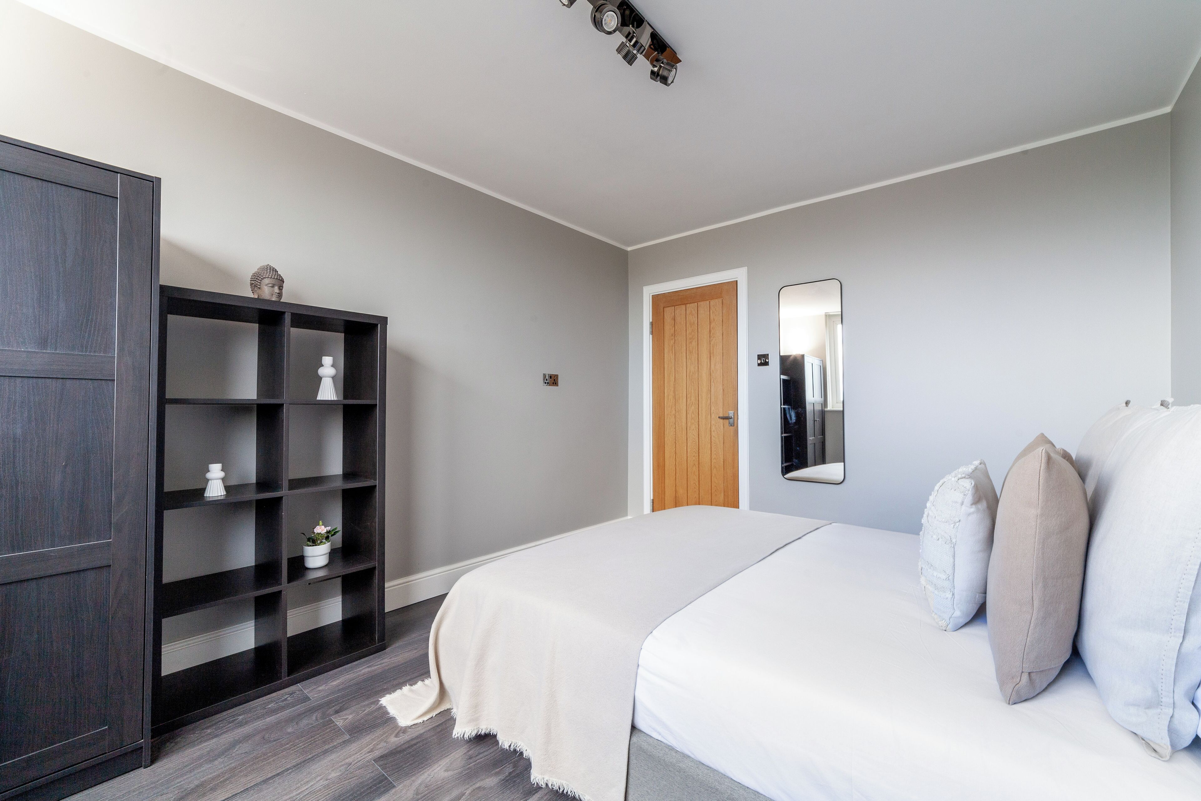 A bedroom with a bed, a wardrobe, a mirror, and a door.