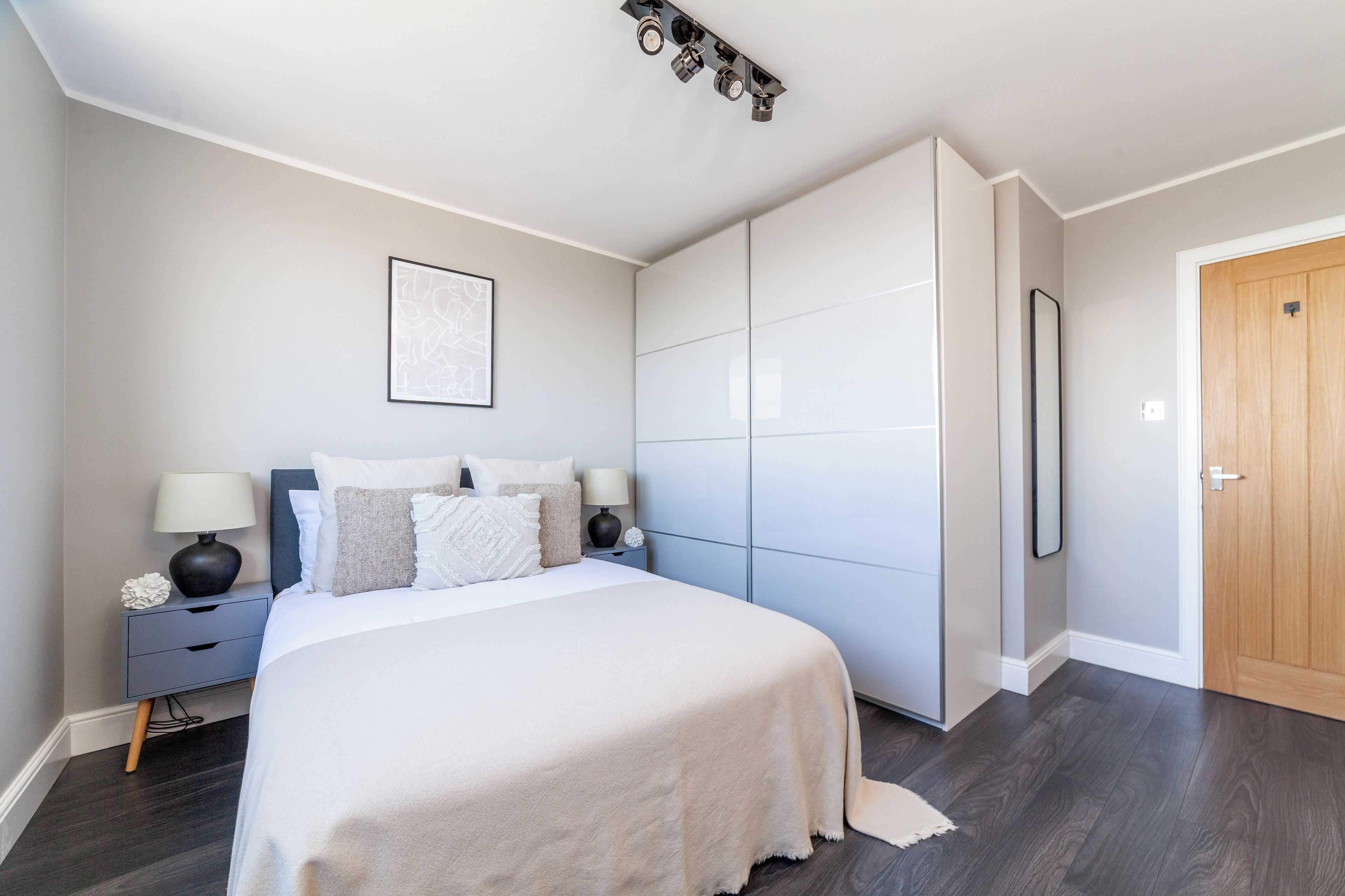 Une chambre à coucher avec un lit, des tables de chevet, une armoire et une porte.