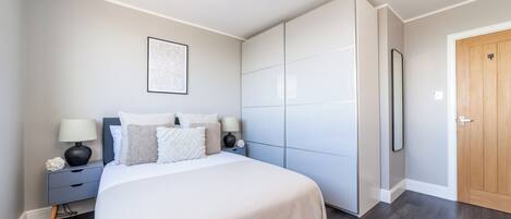 Une chambre à coucher avec un lit, des tables de chevet, une armoire et une porte.