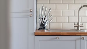 A kitchen with light grey cabinets, a wooden countertop, and a sink with a modern faucet. - The Old Street Luxury Apartment (London)