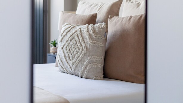 A bedroom with a bed, pillows, a bedside table, and a mirror reflecting the room. - The Old Street Luxury Apartment (London)