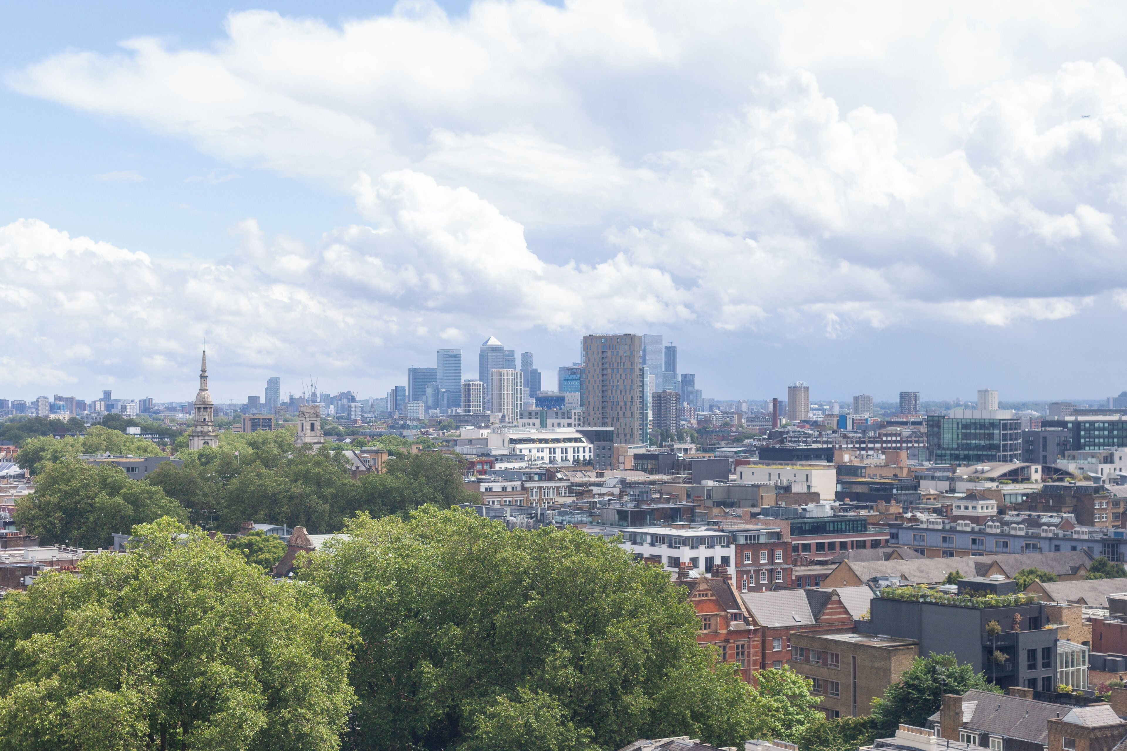 A cityscape with a mix of modern and historic buildings, dense urban layout, and a prominent church spire.