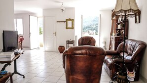 A spacious living room with a leather sofa, a television, and a decorative lamp. - Le Nid de Gilles (Collioure)