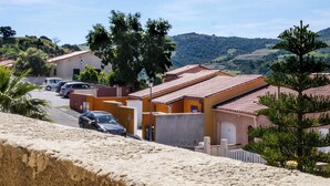 A residential area with houses, a street, and a hilly landscape in the background. - Le Nid de Gilles (Collioure)