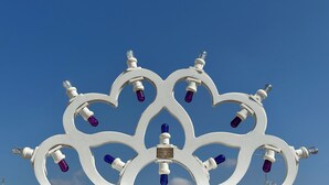 Una estructura blanca y ornamentada con múltiples luces contra un cielo azul despejado.