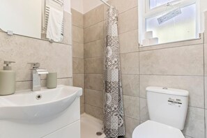 Une salle de bain avec un lavabo blanc, des toilettes et un rideau de douche à motifs géométriques.