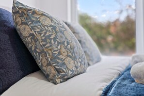 Un lit avec un oreiller à motifs floraux et une couverture bleue.