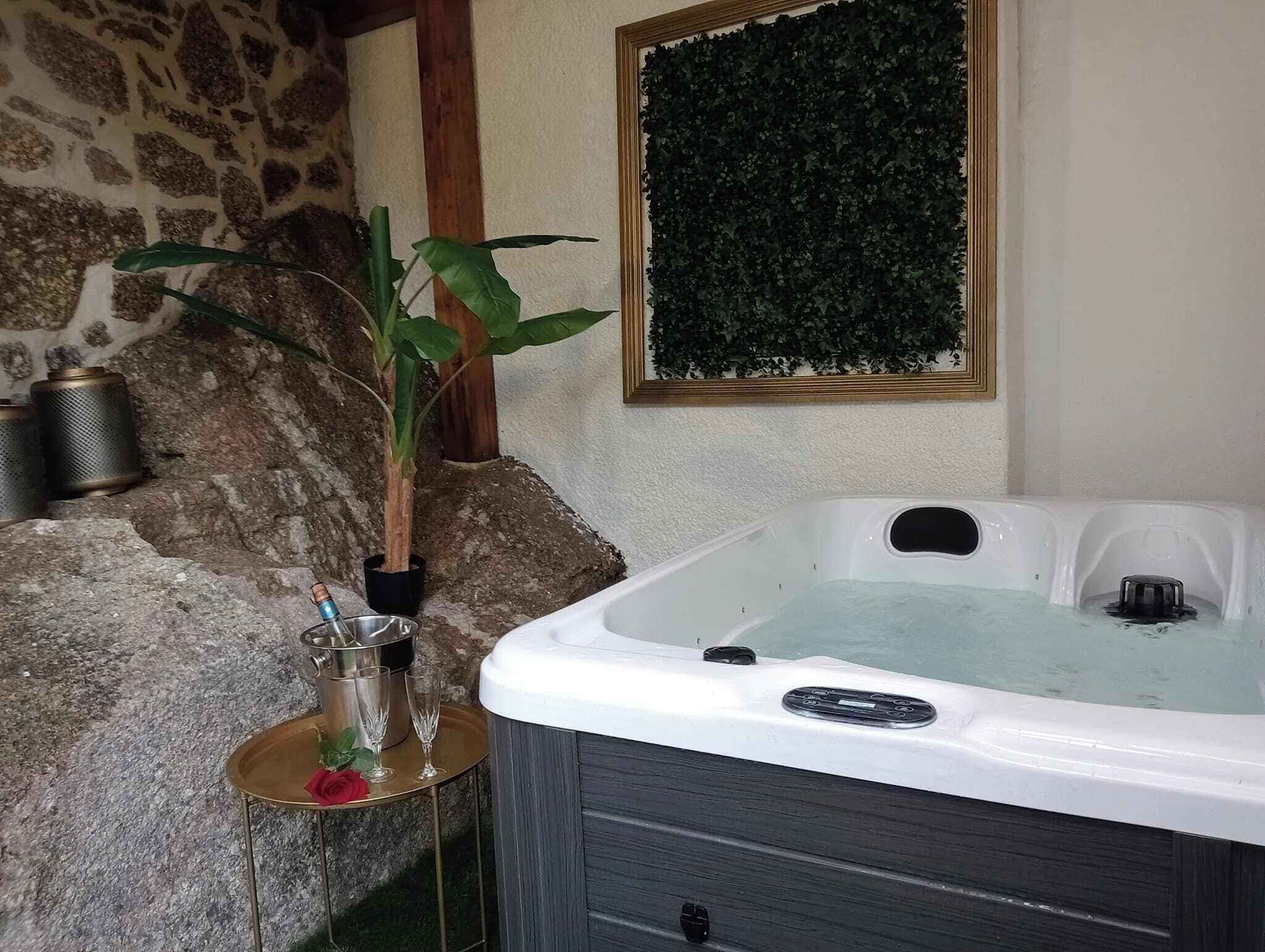 A spa area with a hot tub, a potted plant, and a small table with a glass and a rose.