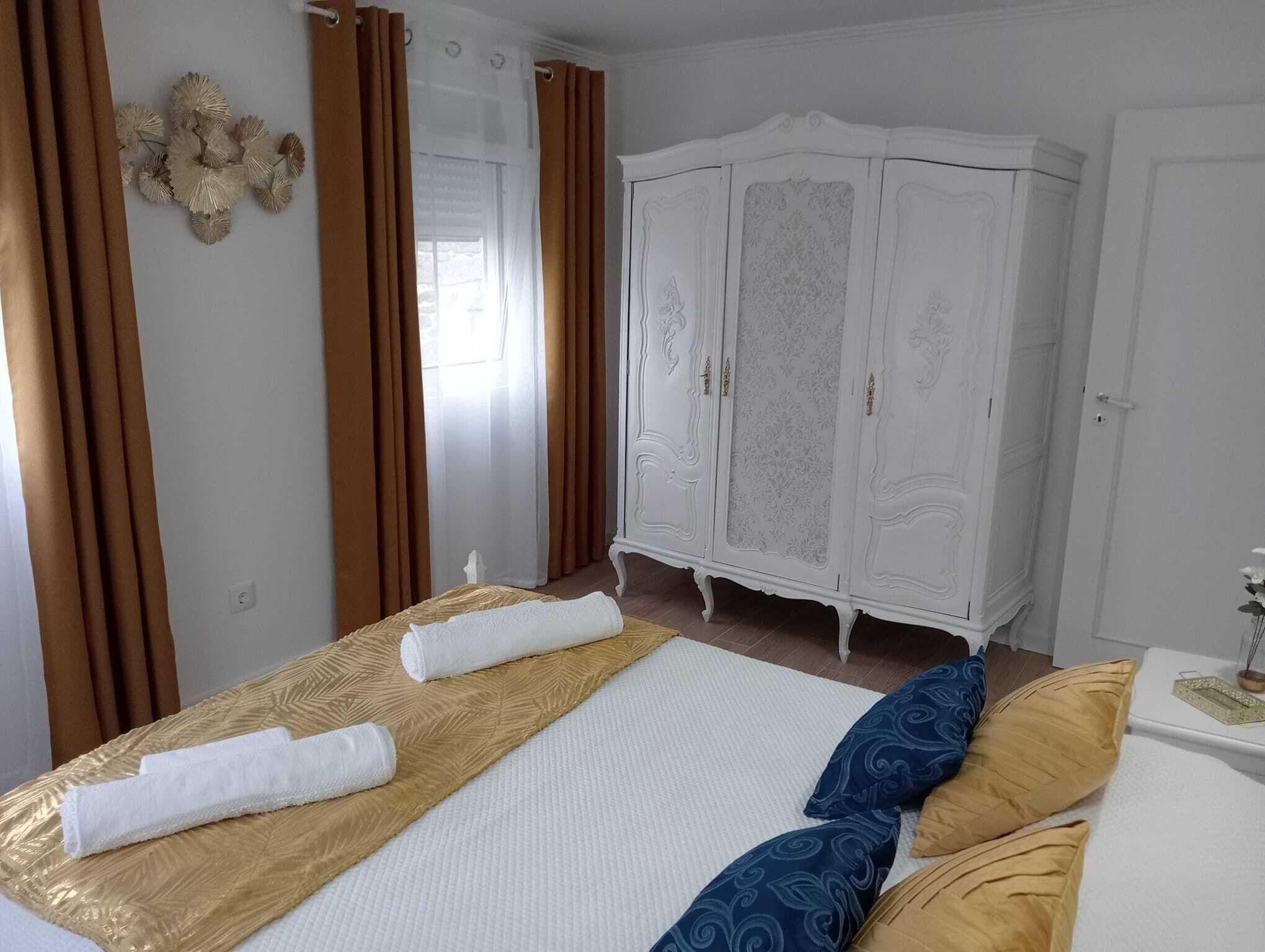 A hotel room with a large bed, a white wardrobe, and brown curtains.