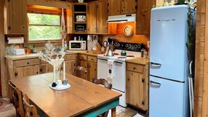 Una cocina rústica con armarios de madera, estufa, microondas y refrigerador.
