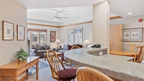 A modern kitchen with a granite countertop, wooden chairs, and a dining table.