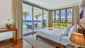 A bedroom with a large bed, a nightstand, a fruit bowl, and a view of the ocean. - Abogo Da Nang OceanFront Luxury Villa (Da Nang)