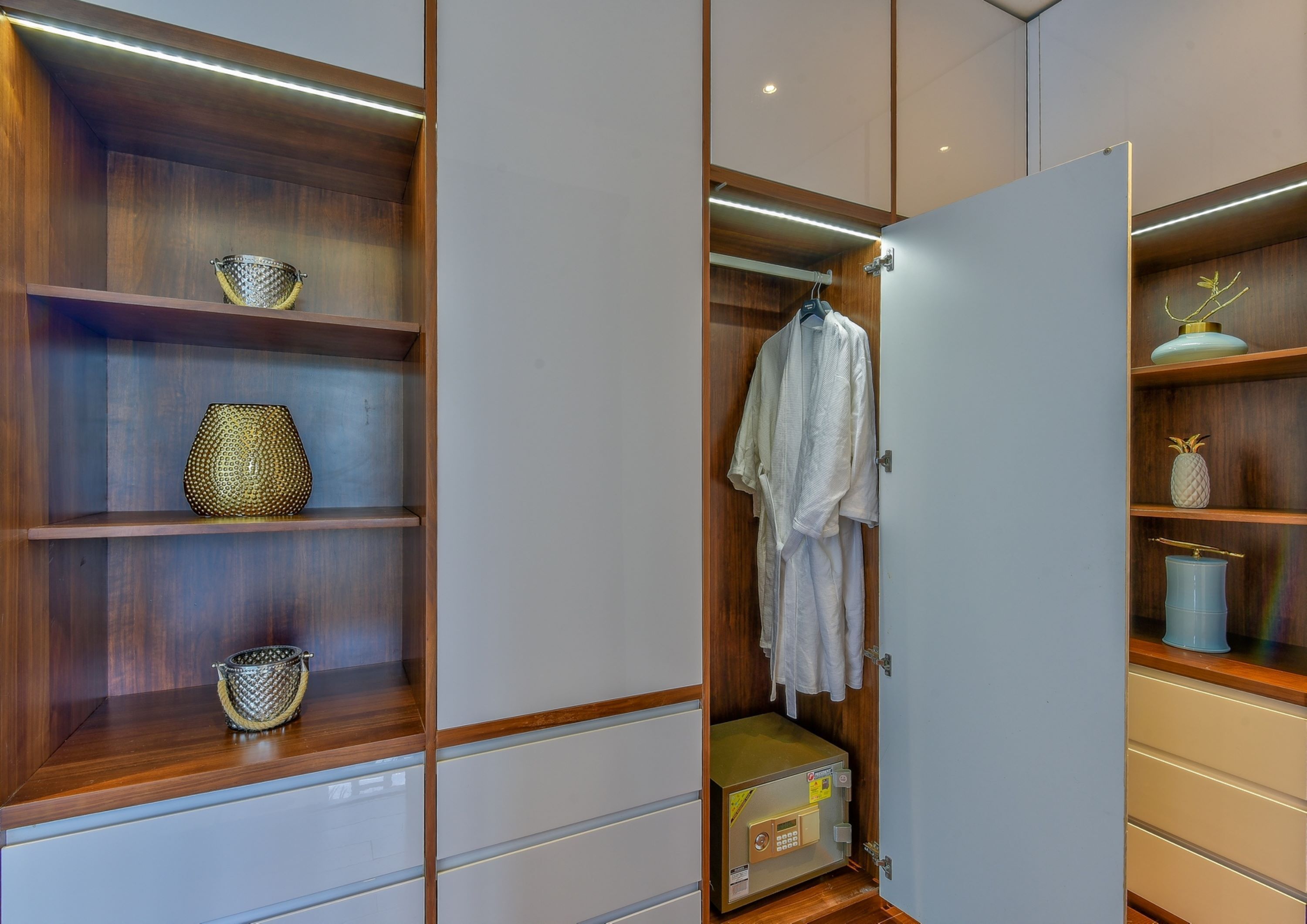 A walk-in closet with wooden shelves, a hanging robe, and a safe.