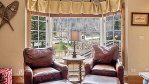 A corner room with two leather chairs, a small table, and a bay window with curtains. - The Charter at Beaver Creek F3505 (Beaver Creek)