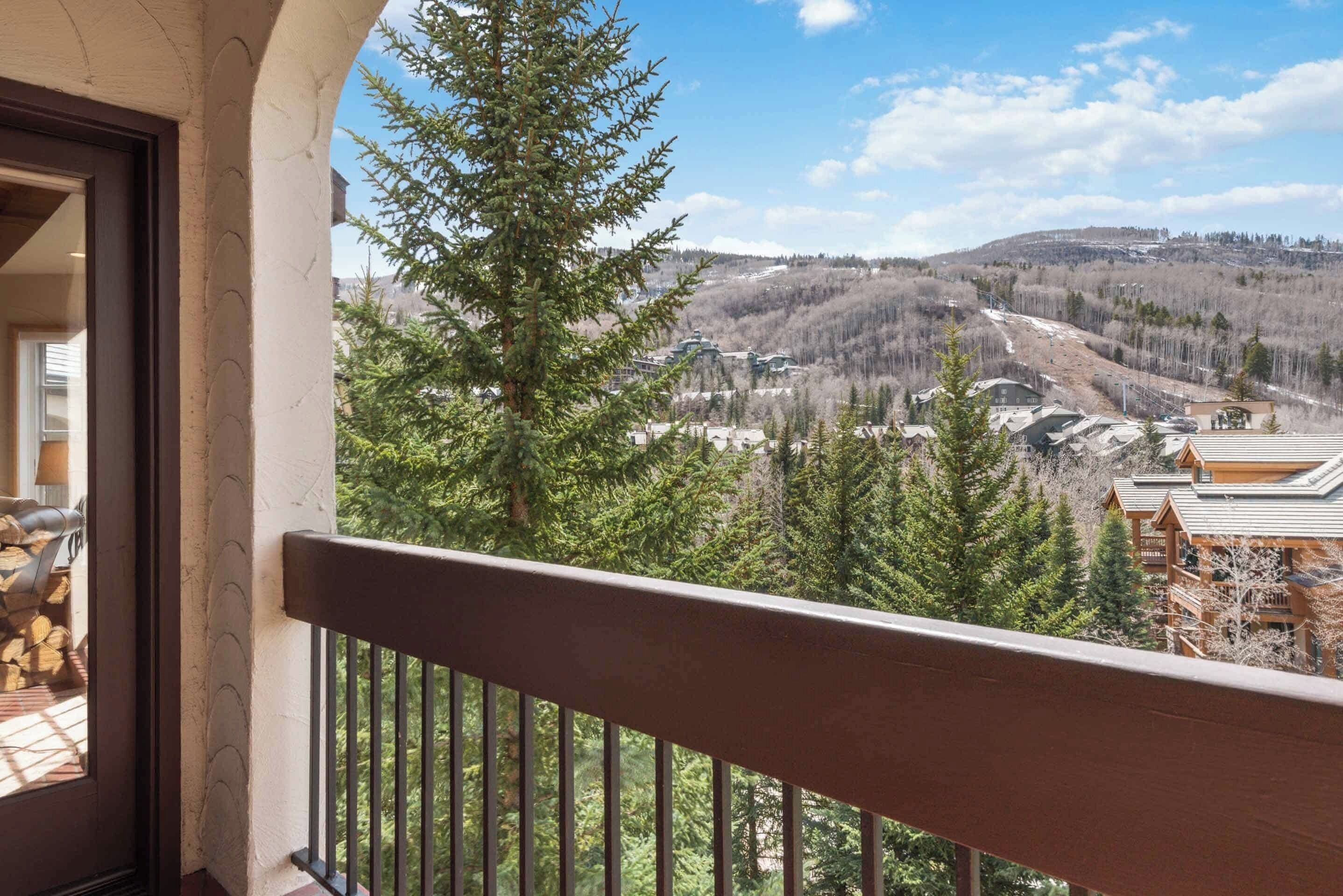 Un balcon offrant une vue sur un paysage montagneux, avec des arbres et des bâtiments.