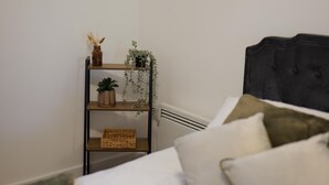 Ein Schlafzimmer mit einem Bett, einem Nachttisch mit Pflanze und einer Heizung.