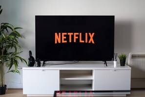Een flatscreen-tv op een witte entertainmentkast, waarop 'NETFLIX' wordt weergegeven.