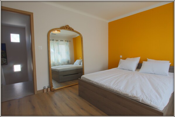 Ein Schlafzimmer mit einem großen Spiegel, einem Bett mit weißer Bettwäsche und einem Holzboden.