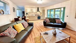 Ein geräumiges Wohnzimmer mit zwei Sofas, einem Couchtisch und einer Küche im Hintergrund.