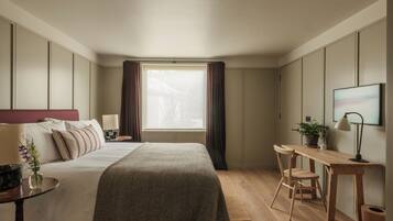 Une chambre d’hôtel avec un lit, un bureau, une chaise et une fenêtre avec des rideaux.