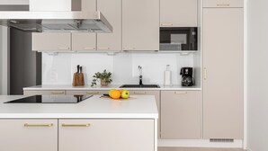 A modern kitchen with a central island, stainless steel appliances, and light-colored cabinetry.