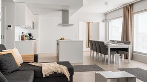 A modern living room with a sofa, a coffee table, and a dining area with a table and chairs.