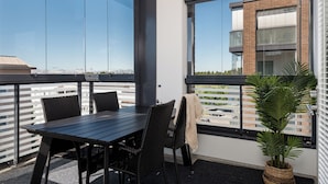 A balcony with a table and chairs, large windows, and a potted plant.