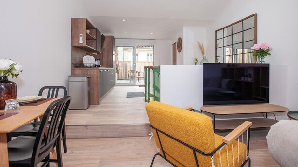Un espacio de estar moderno con comedor, cocina y televisor.
