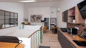 Una cocina moderna con armarios de madera, un comedor con mesa y sillas, y una escalera que conduce a un nivel superior.