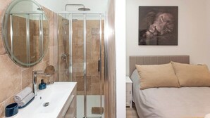 Un baño con ducha de vidrio, un espejo redondo y un lavamanos blanco.
