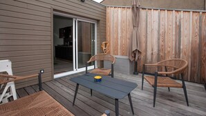 Un patio con una mesa y sillas, una puerta corrediza de vidrio y una valla de madera.