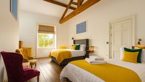 Ein Hotelzimmer mit zwei Betten, einer Holzbalkendecke, einem Fenster, einem Stuhl und einer Heizung.