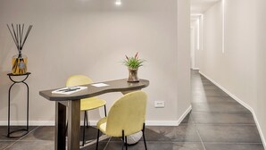Een moderne eetruimte met een gebogen tafel, twee gele stoelen, een potplant en een hoge rietverdamper.
