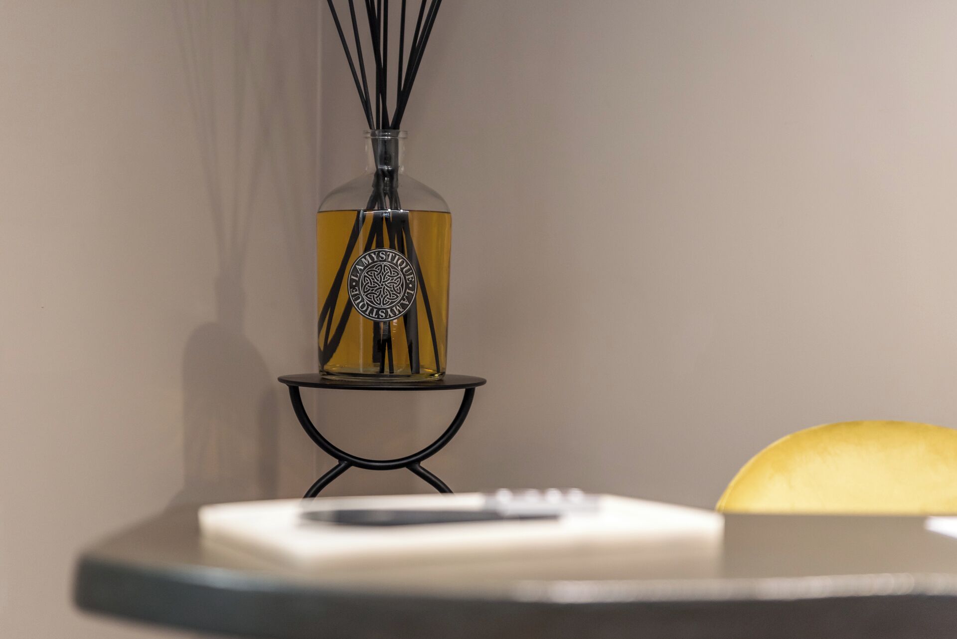 Une bouteille en verre ornée d’une étiquette décorative et de rubans noirs, posée sur un support en métal noir.