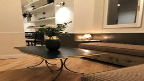 Ett modernt vardagsrum med ett mörkt soffbord, en randig soffa och en vas med blommor.