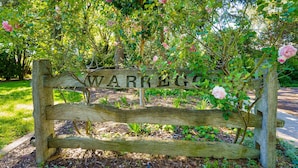 A wooden bench with the inscription "WARRINGTON" in a garden setting. - Garden Precinct 3BR, Walking distance to Airport (Pialligo)