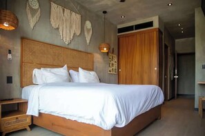 Quarto com cama grande, cabeceira de madeira e tapeçaria de macramé na parede.