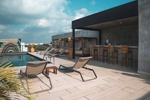 A rooftop pool area with lounge chairs, a bar, and a covered seating area. - Safe & Beautiful Studio: Parking, Padel & Pool (Tulum)
