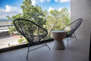 A balcony with two black wire-framed chairs and a round table.