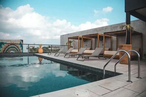 A rooftop pool with lounge chairs and a concrete structure.